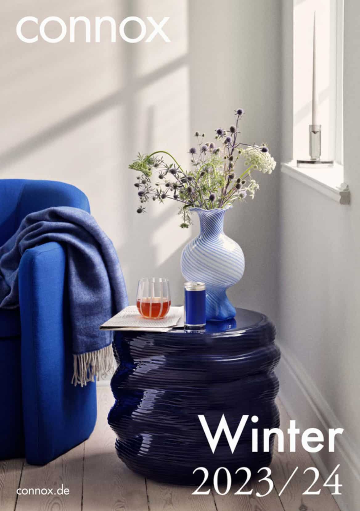 Connox catalog cover winter 2023-2024. A blue sofa with blue coffee table, light coming from window.