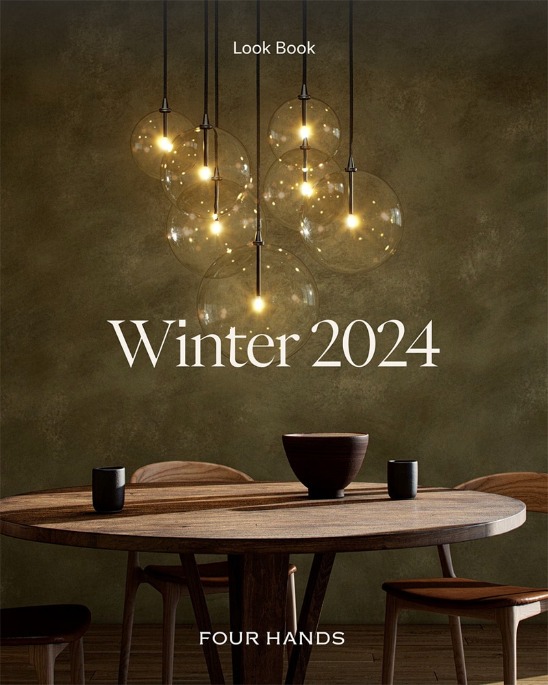 Four hands catalog cover, winter 2024. A stylish dark green background, with a wooden table and beautiful lighting above it.