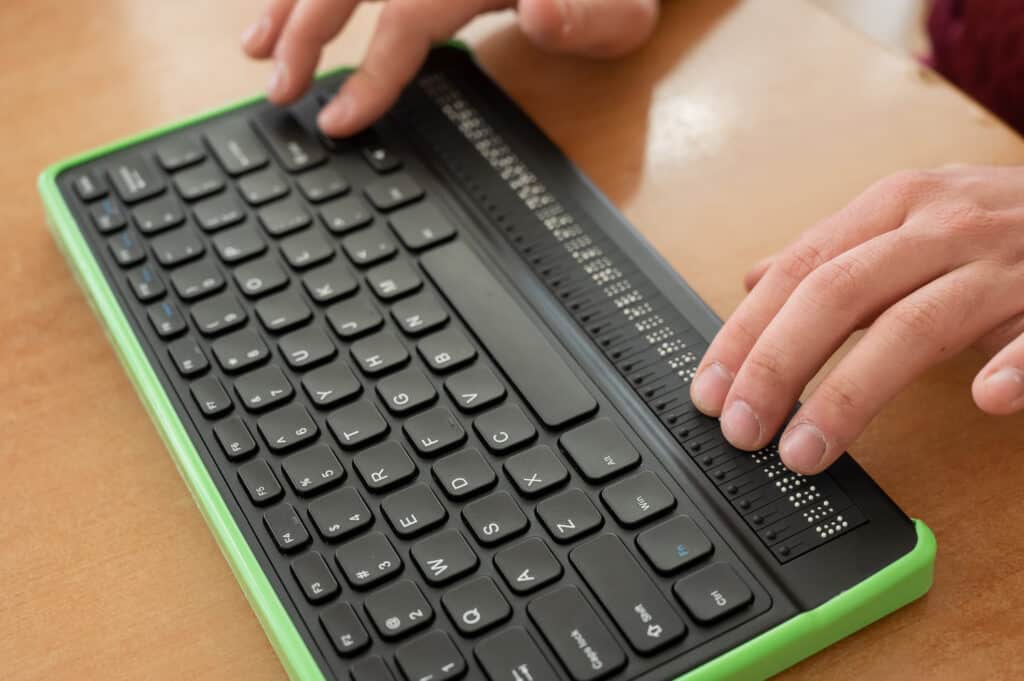 Un ciego utiliza un ordenador con pantalla Braille y teclado de ordenador. Dispositivo inclusivo