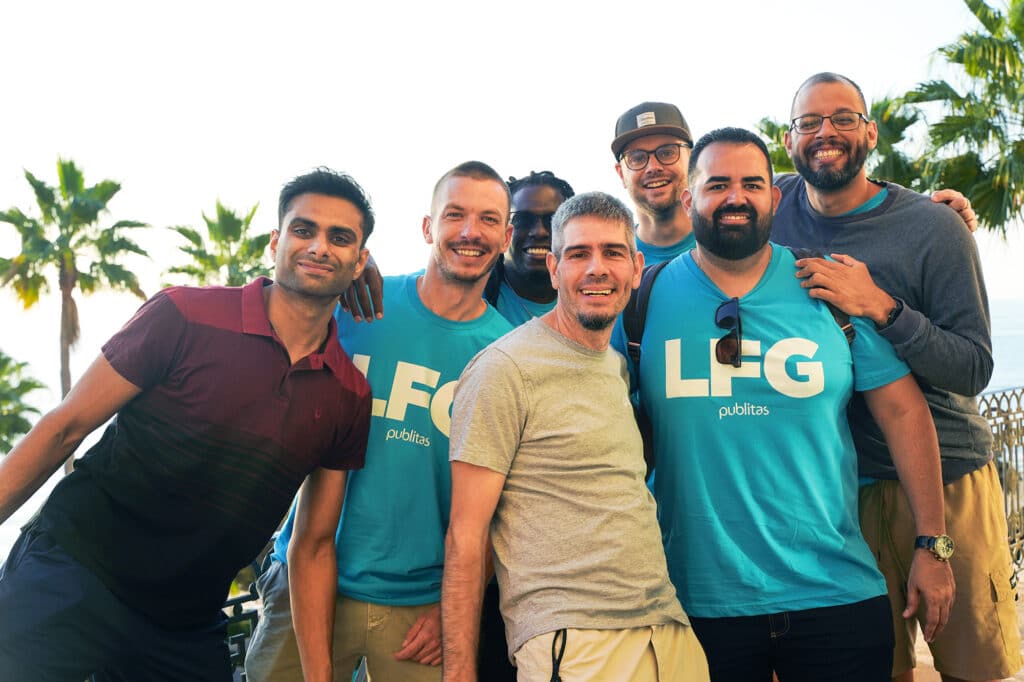 Small group of Publitas employees on the beach leaning in together.