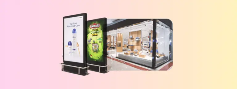 Digital advertising screens outside a modern retail store display two different ads—one for Dove Advanced Care deodorant and the other for Smashers Mega Jurassic Light-Up Dino toy—set against a softly gradient pink-to-yellow background.