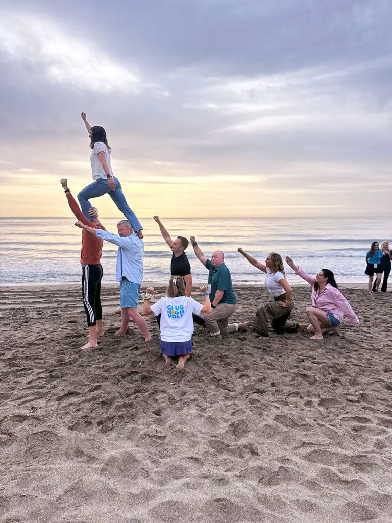 Publitas team activity at the beach. People striking a superhero pose.